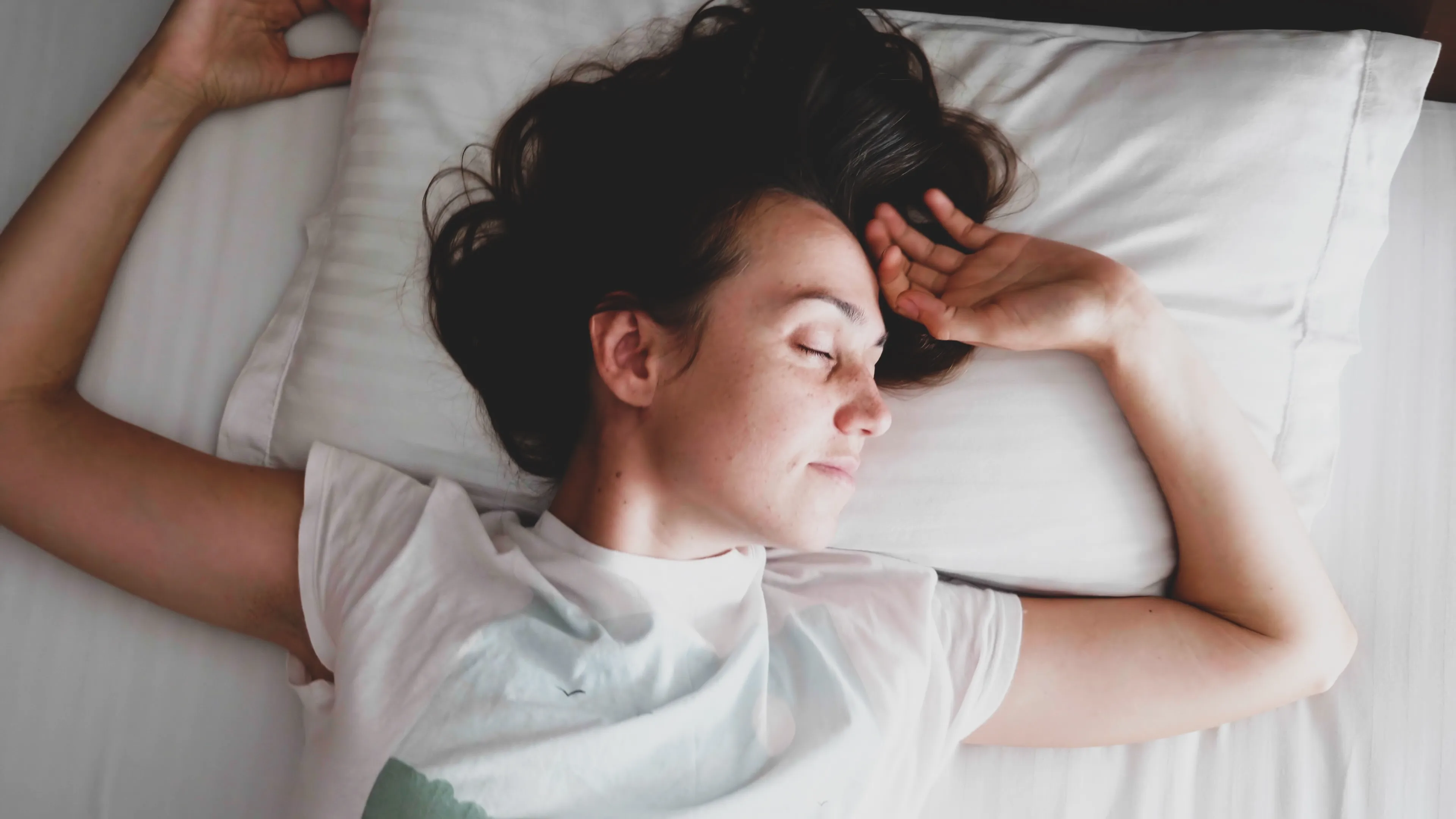 Portrait of young woman is sleeping on the white linen in bed at the morning.