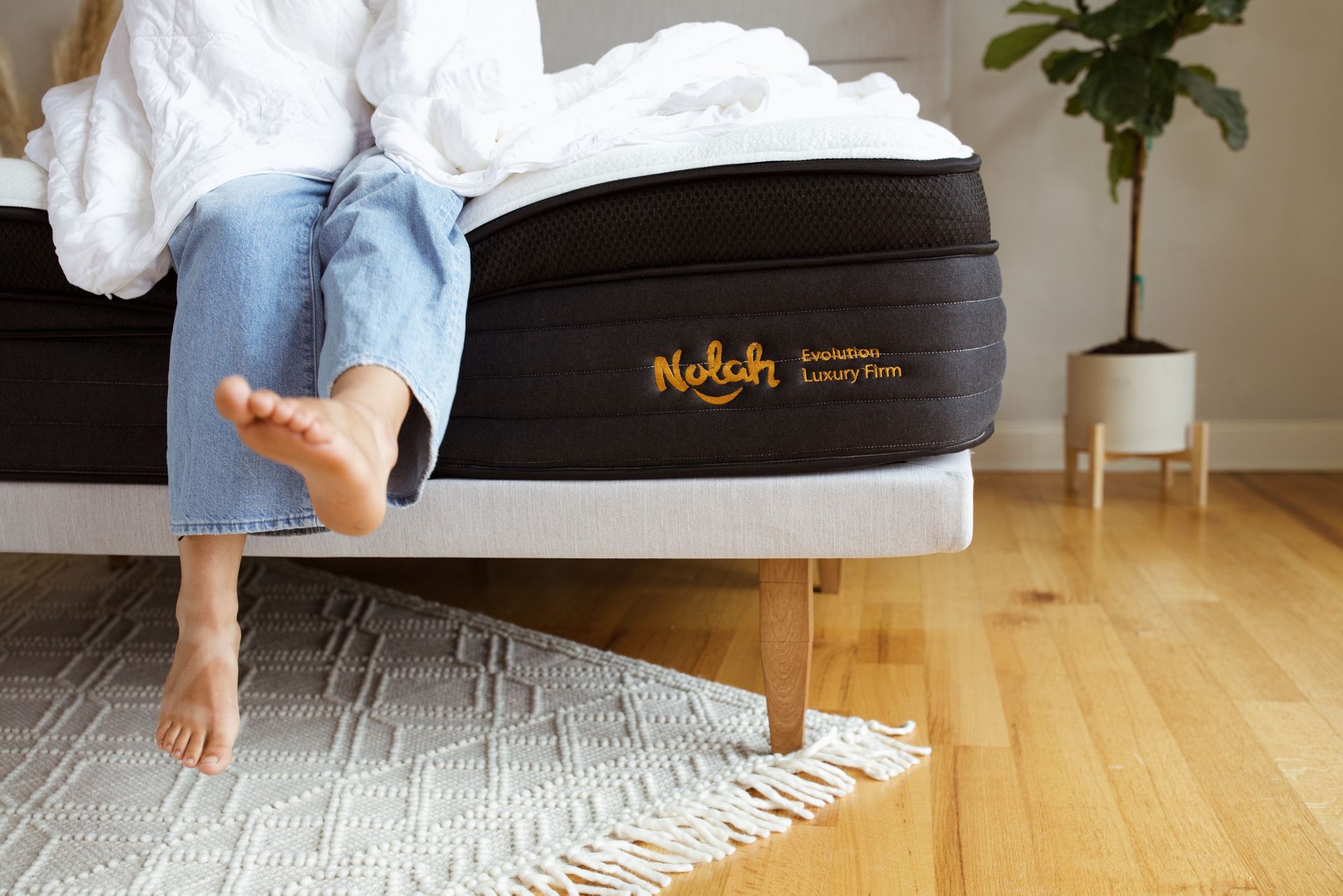 a reviewer sitting on the corner of the nolah evolution mattress