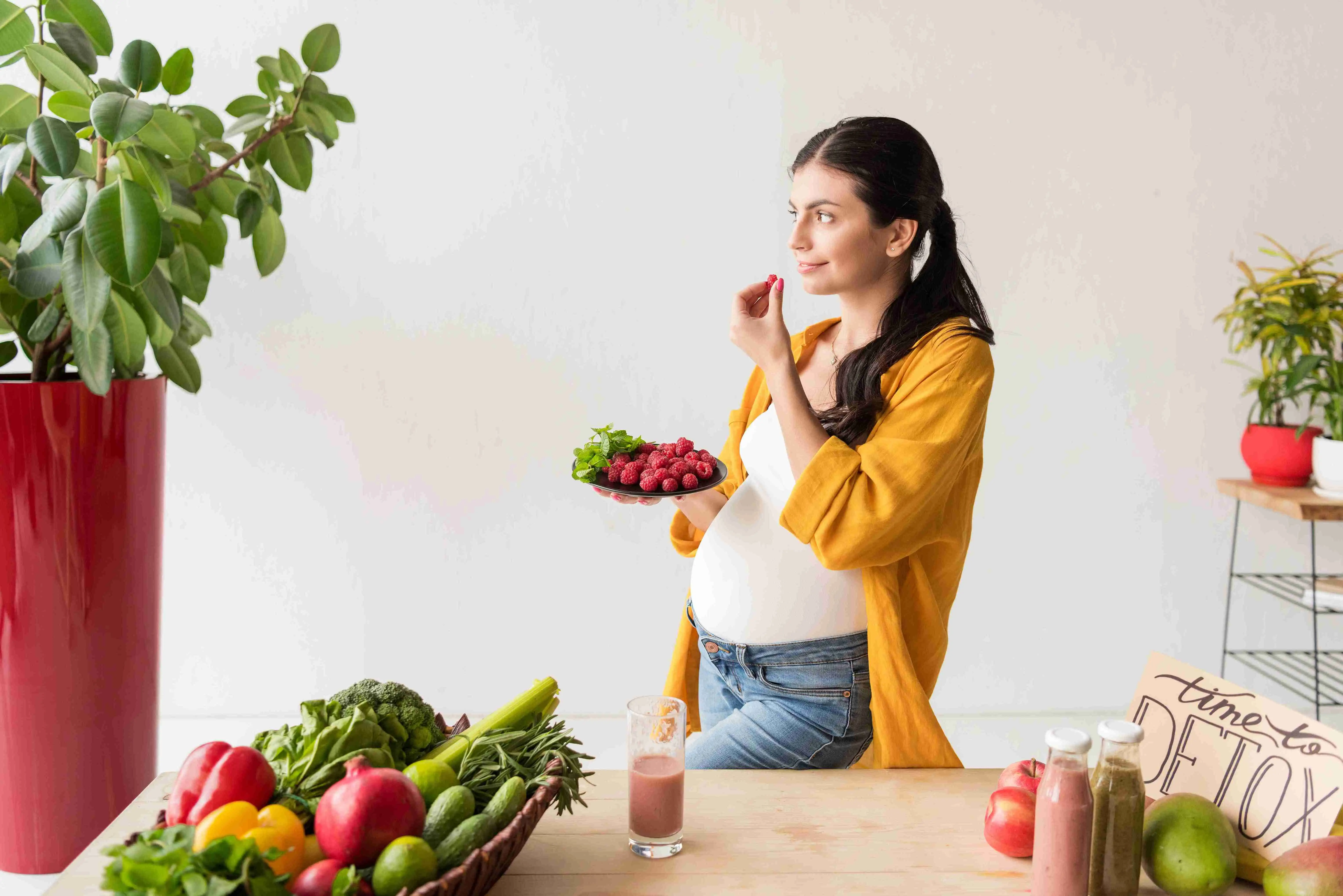 portrait of pregnant woman holding plate with organic food