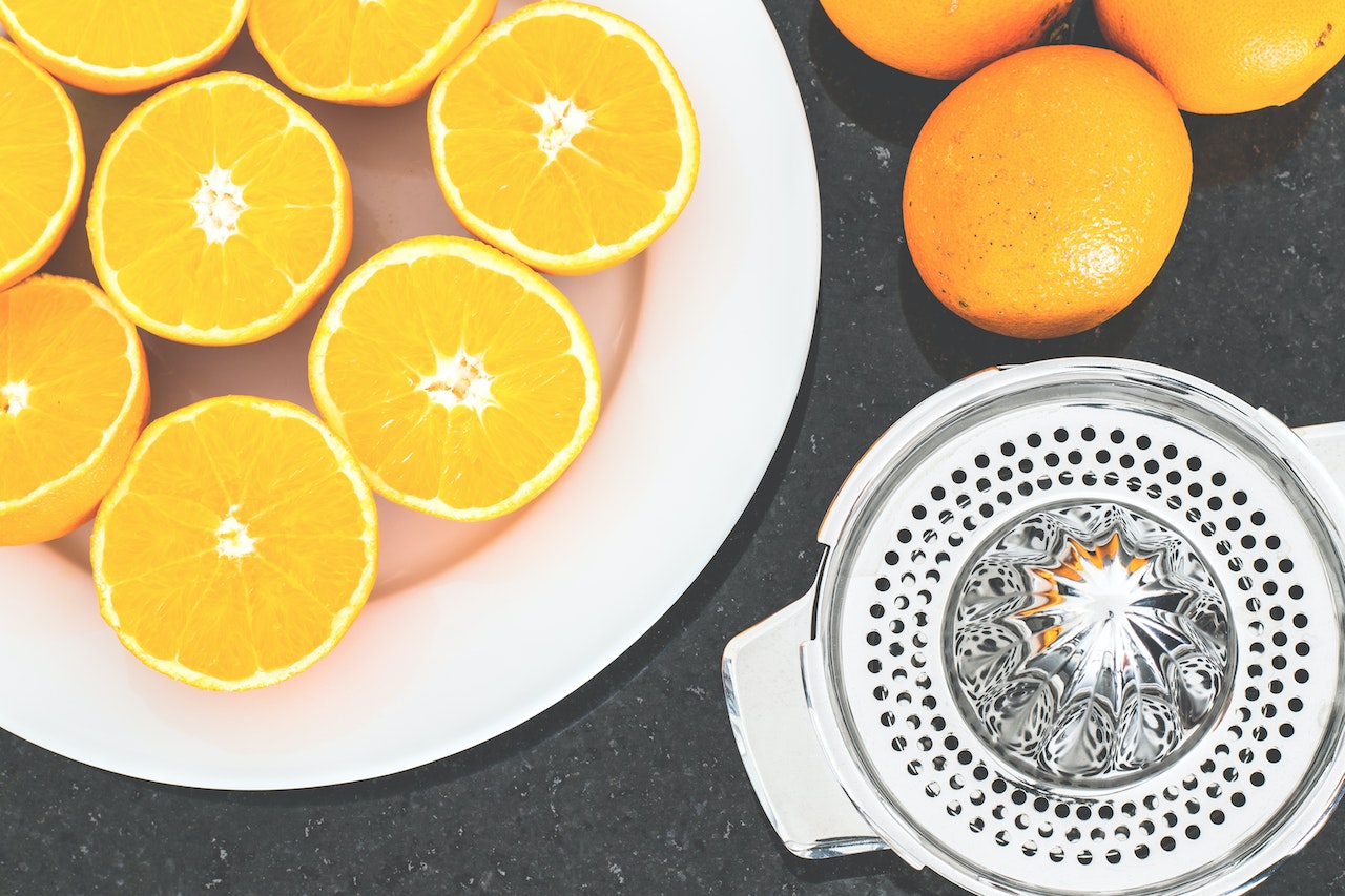 oranges on a plate beside orange juicer