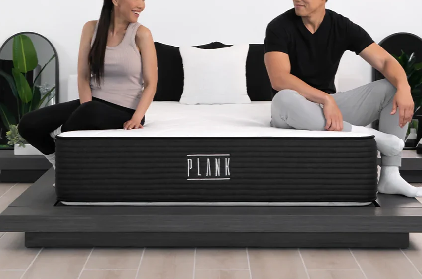 Two reviewers sitting on Plank Firm Luxe mattress