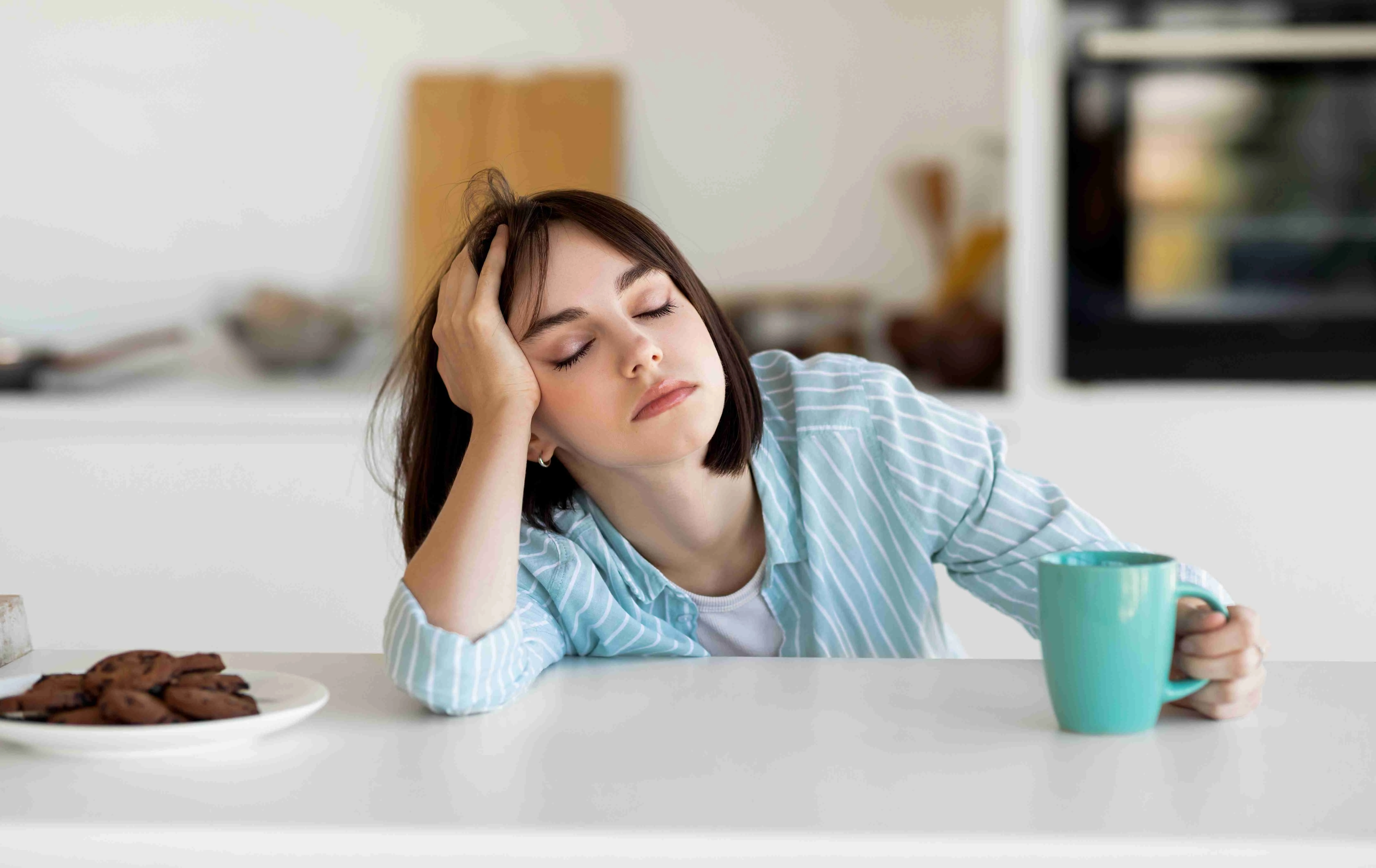 Sleepy young woman drinking coffee, feeling tired, suffering from insomnia and sleeping disorder.