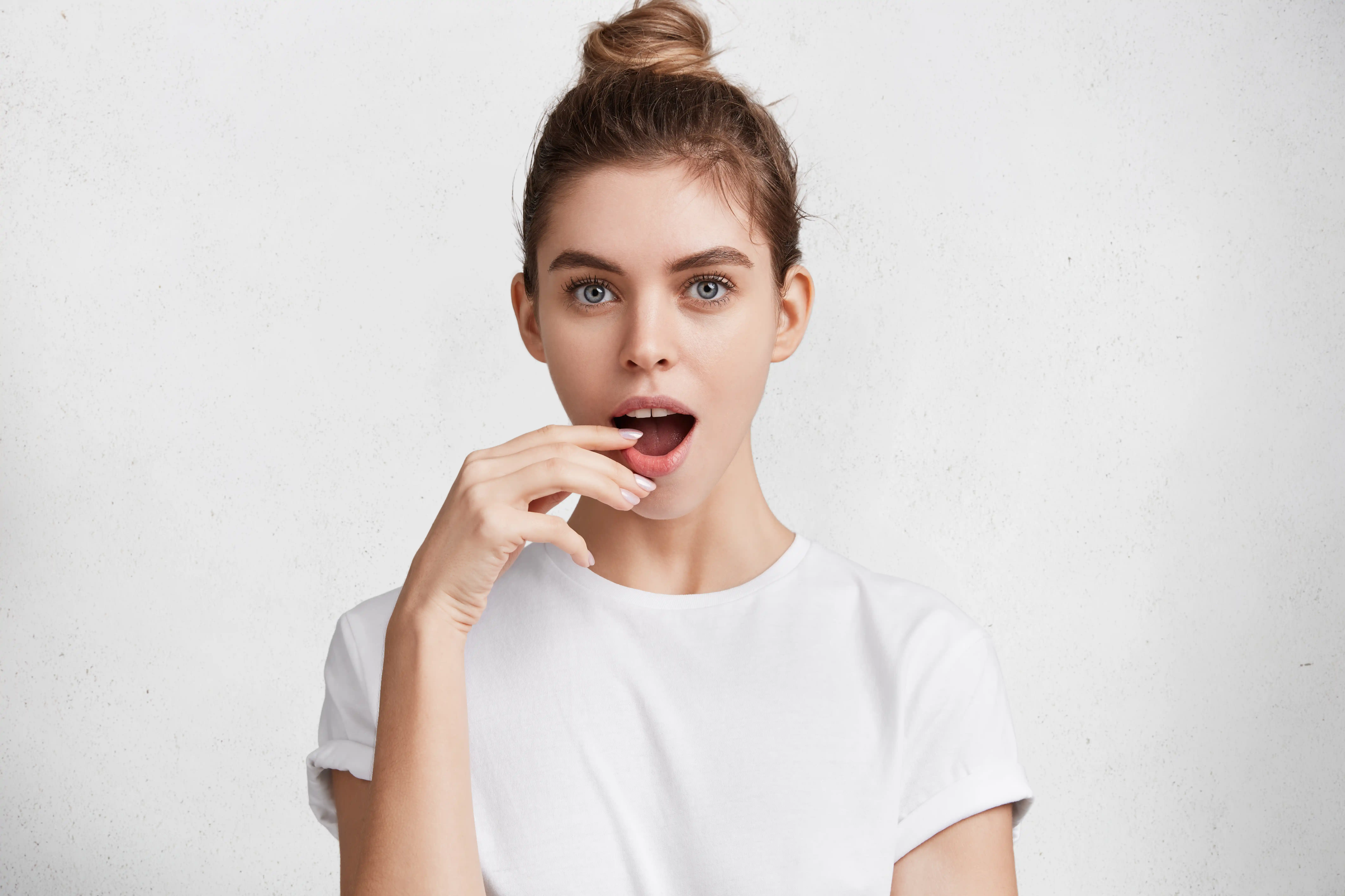 Amazed young female model with pleasant appearance watches with bated breath interesting melodrama,