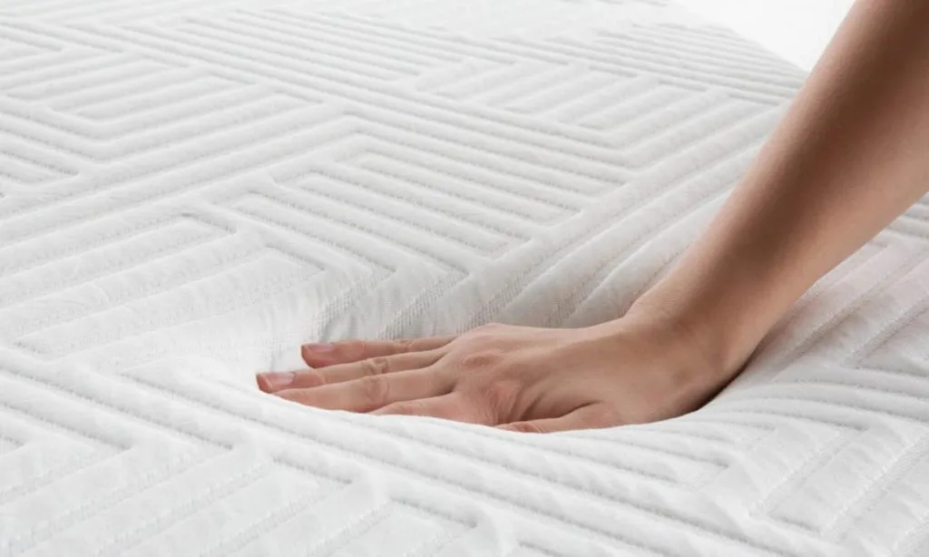 a reviewer hand pushing a mattress