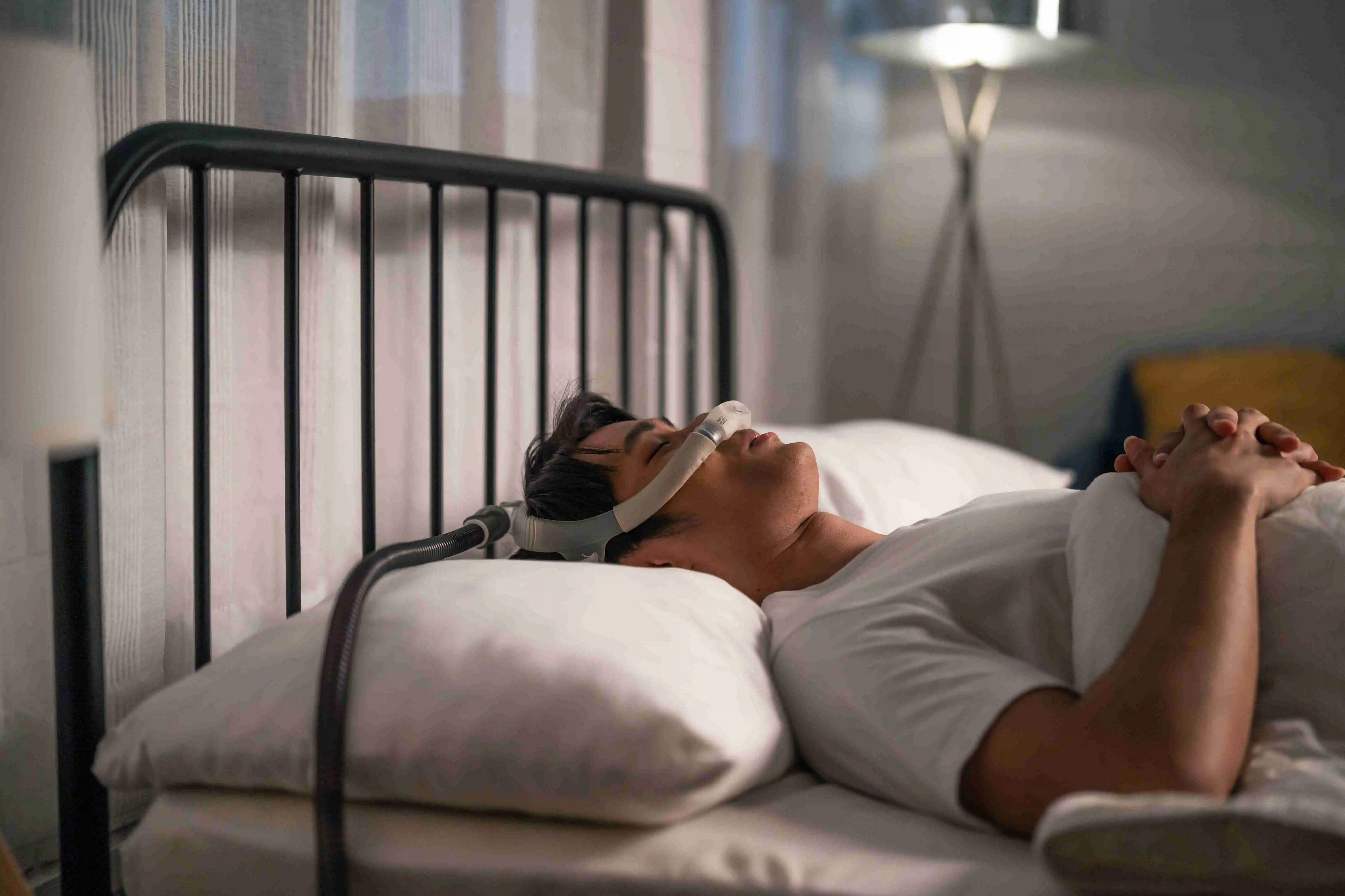 Asian man wearing cpap machine sleeping smoothly all night in bedroom.