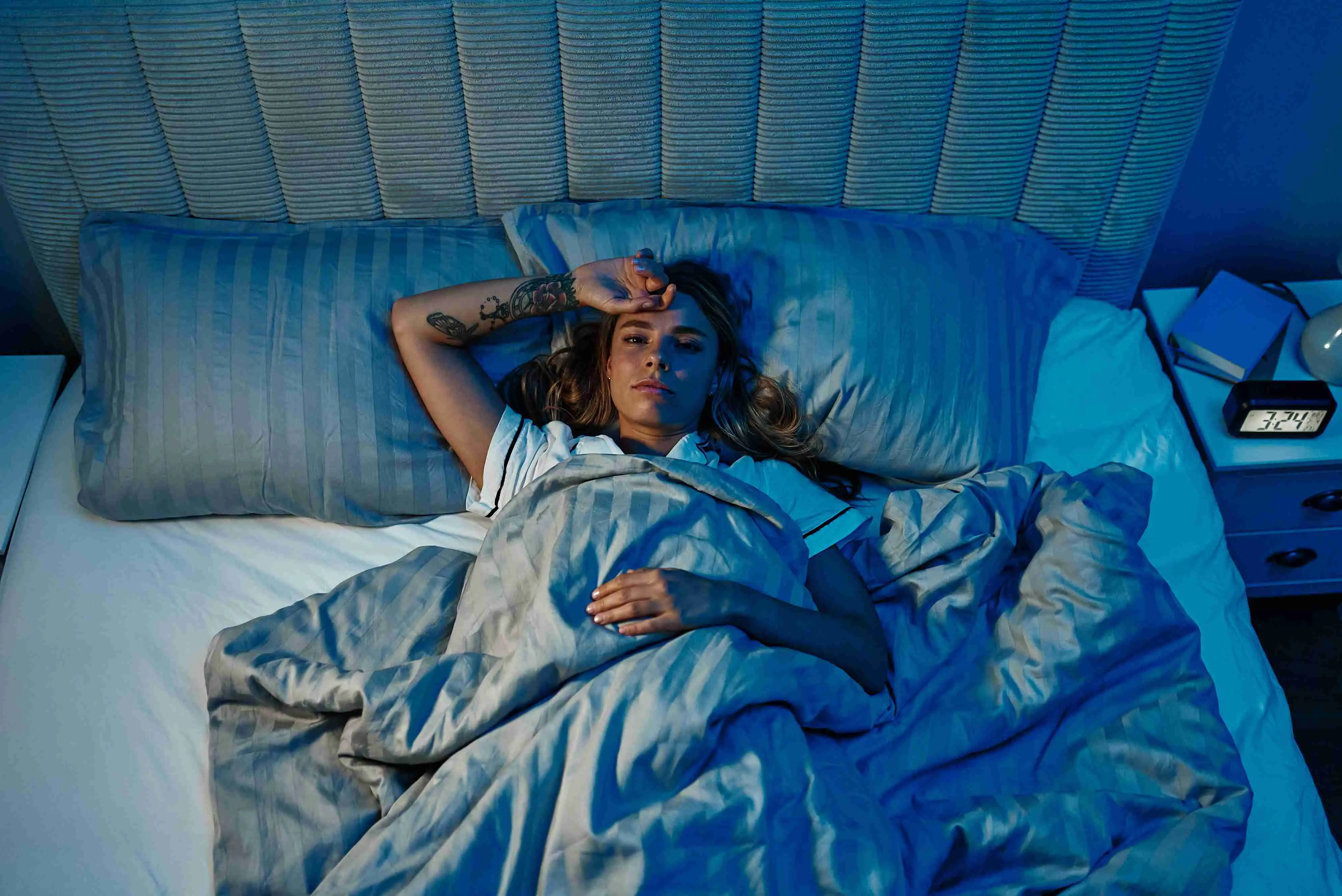 A woman lies awake in bed, showing signs of insomnia and anxiety despite the calming