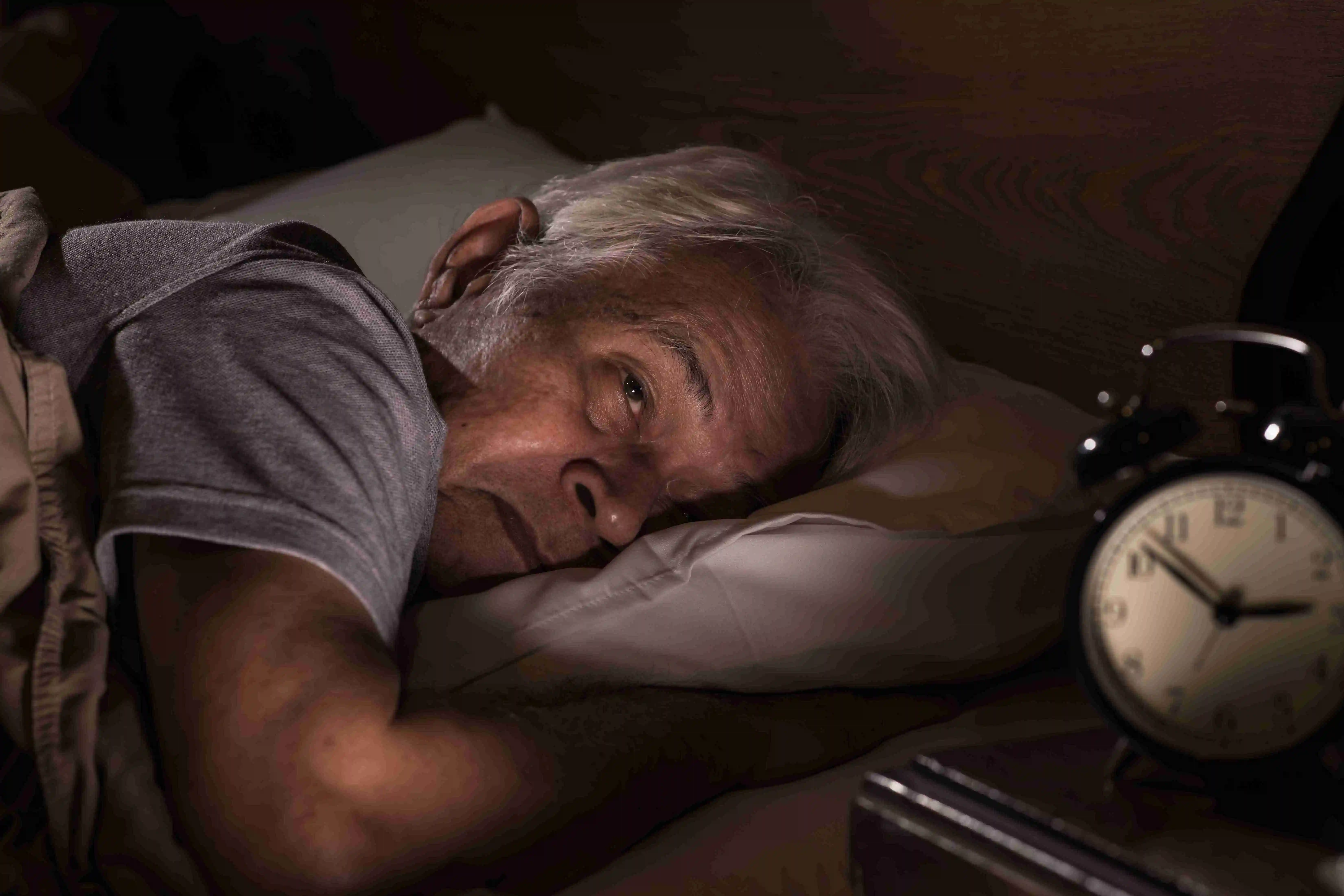 Depressed senior man lying in bed cannot sleep