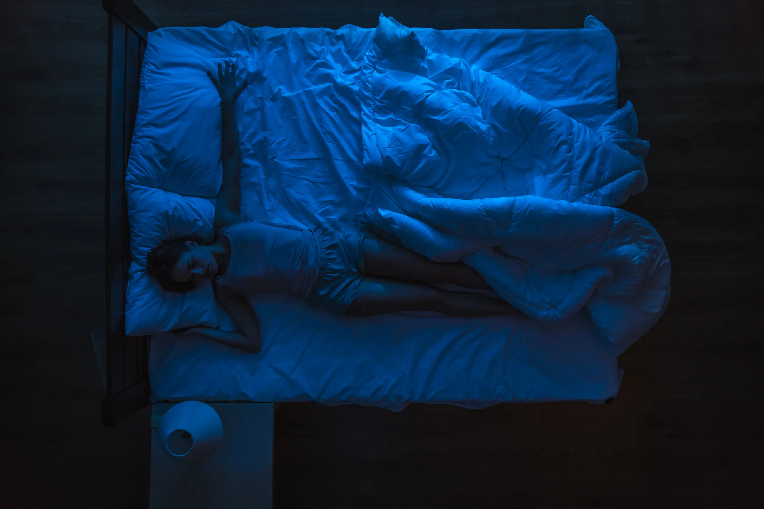 Woman sleeping on a bed at night, viewed from above