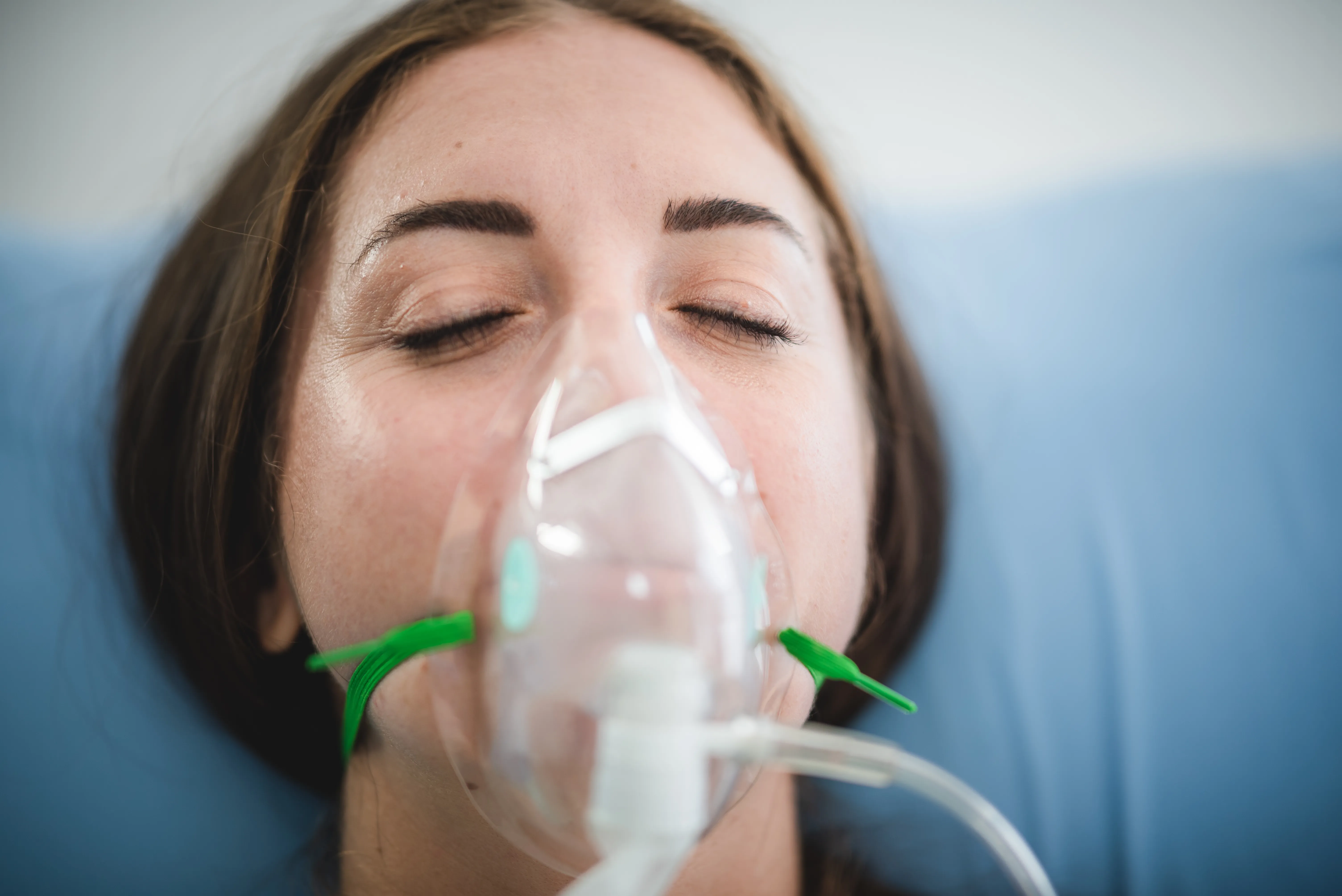 young woman patient receiving oxygen mask lying on a hospital bed, concept of medical and patient
