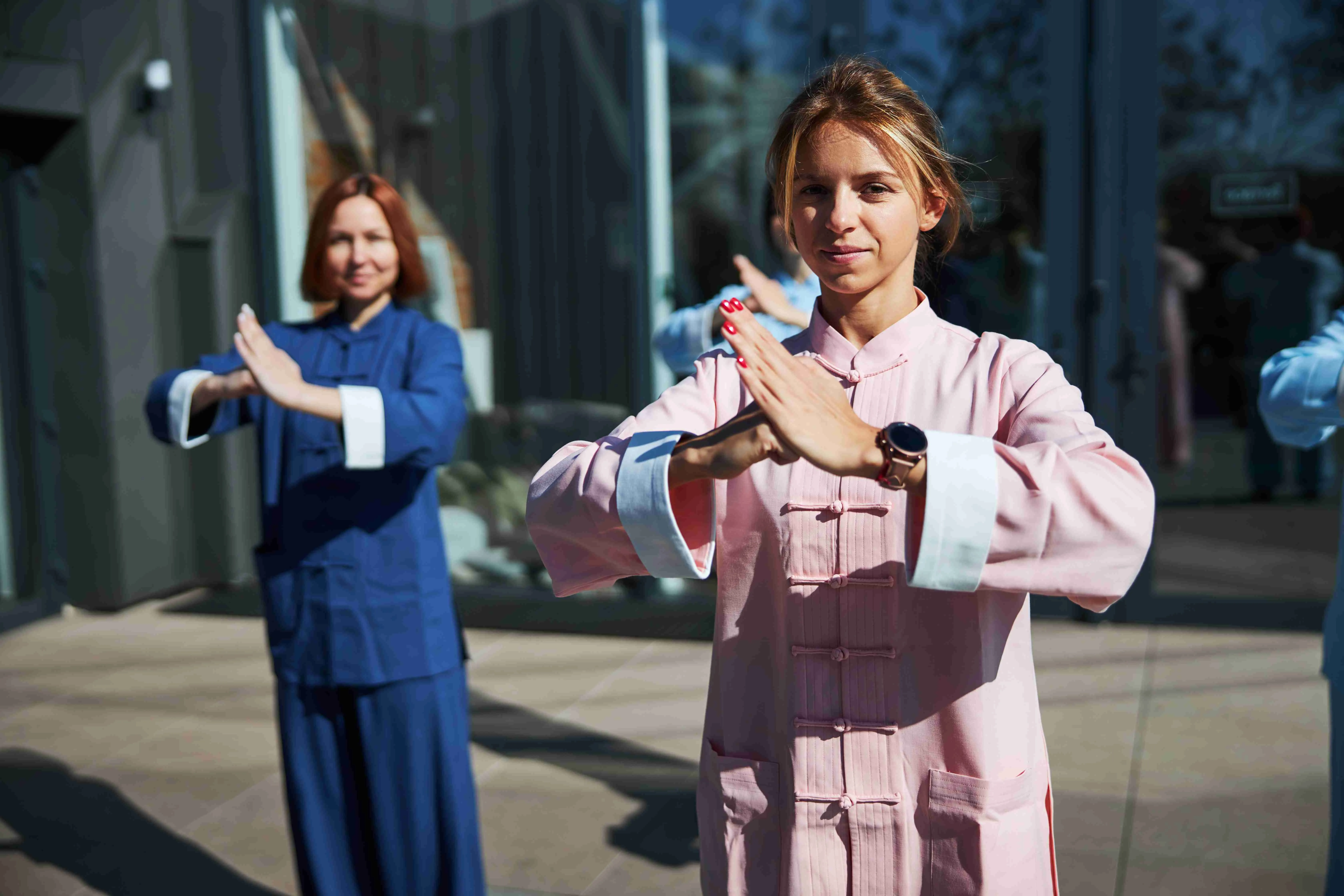 Friendly young ladies looking pleased while practicing traditional Chinese martial arts outdoors