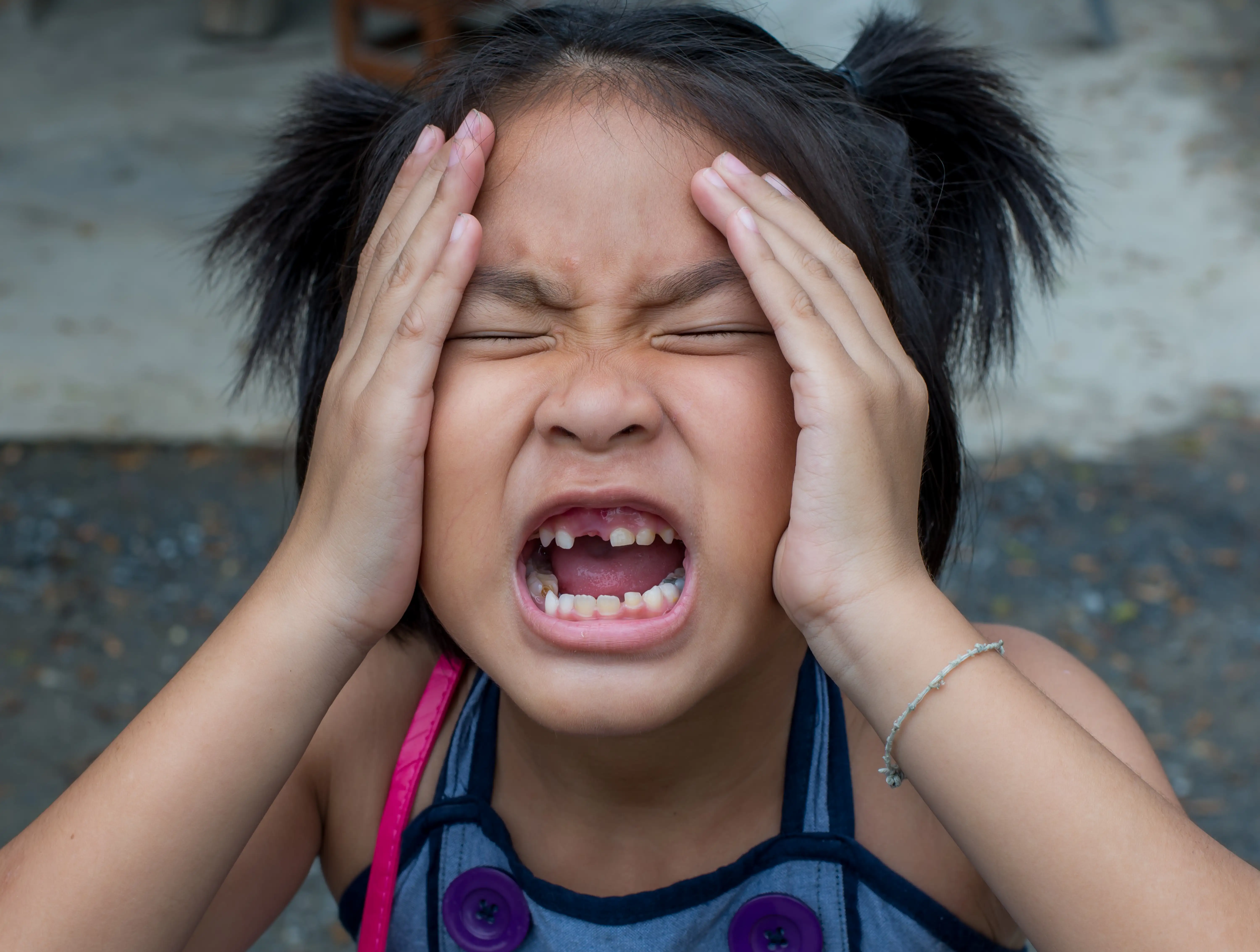 Child holding her cheek because of tooth or jaw discomfort