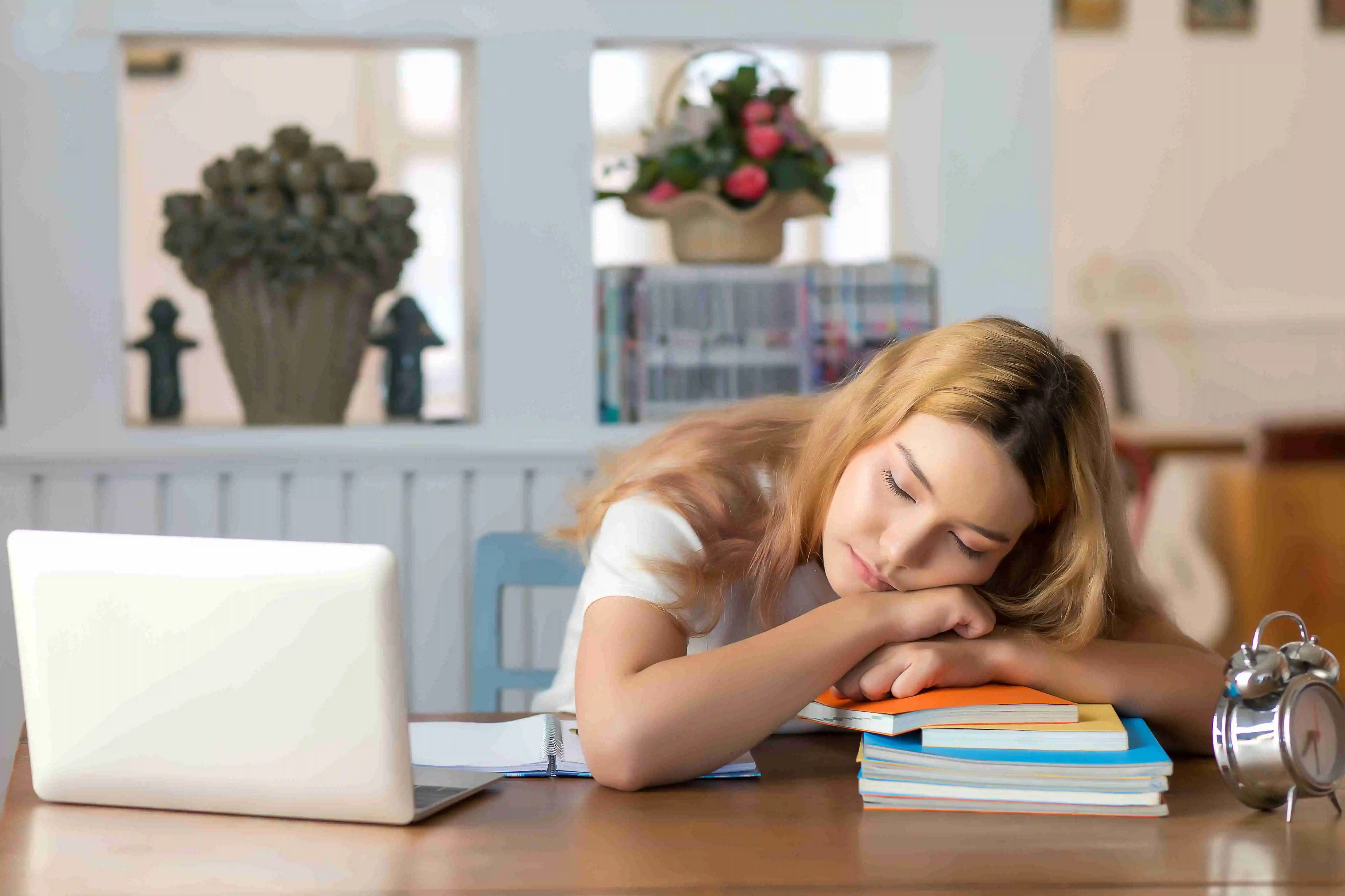 Female student who fell asleep on the desk in the library with a pile of books.