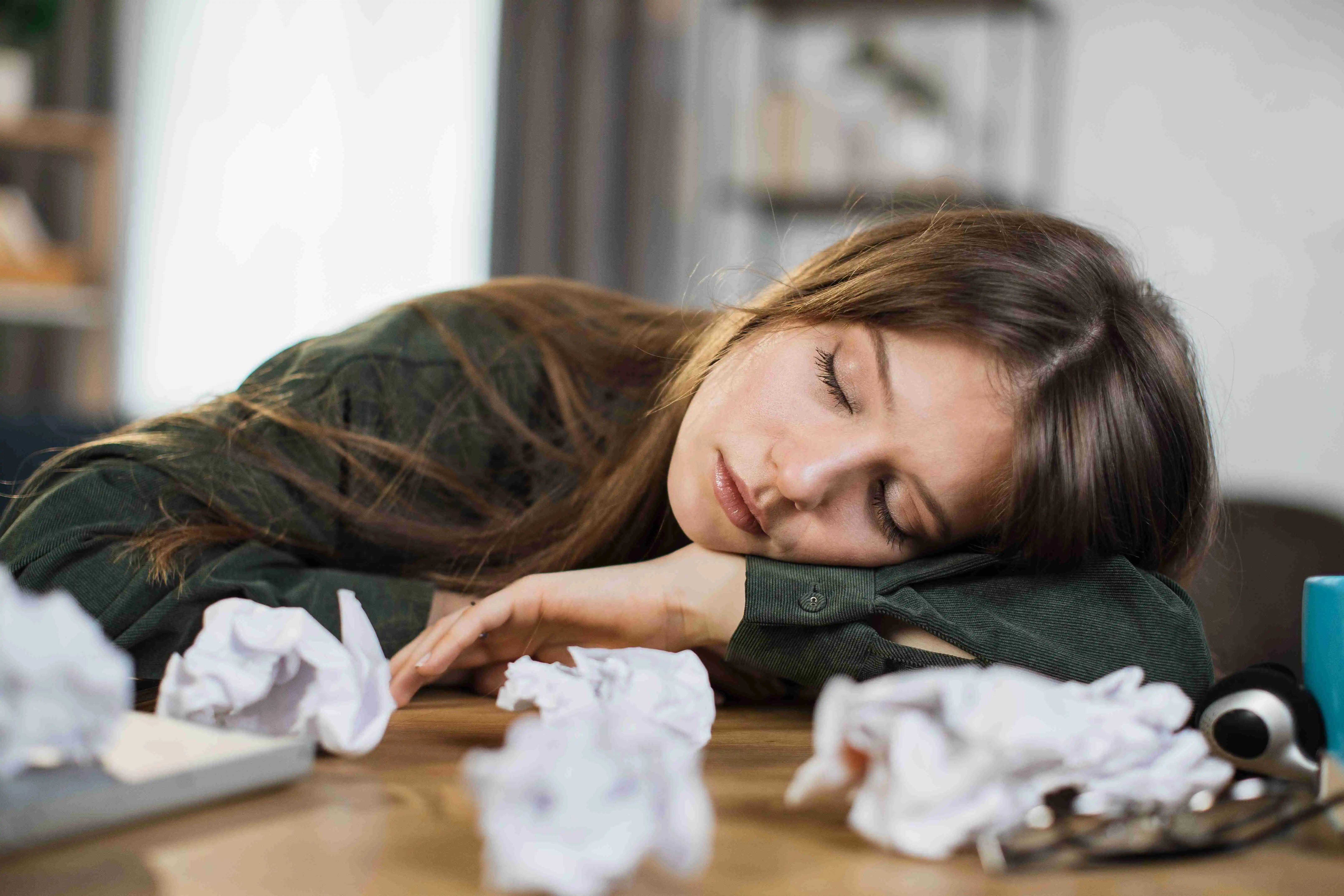 Young frustrated exhausted woman laid her head down on the table sitting at desk with pc laptop