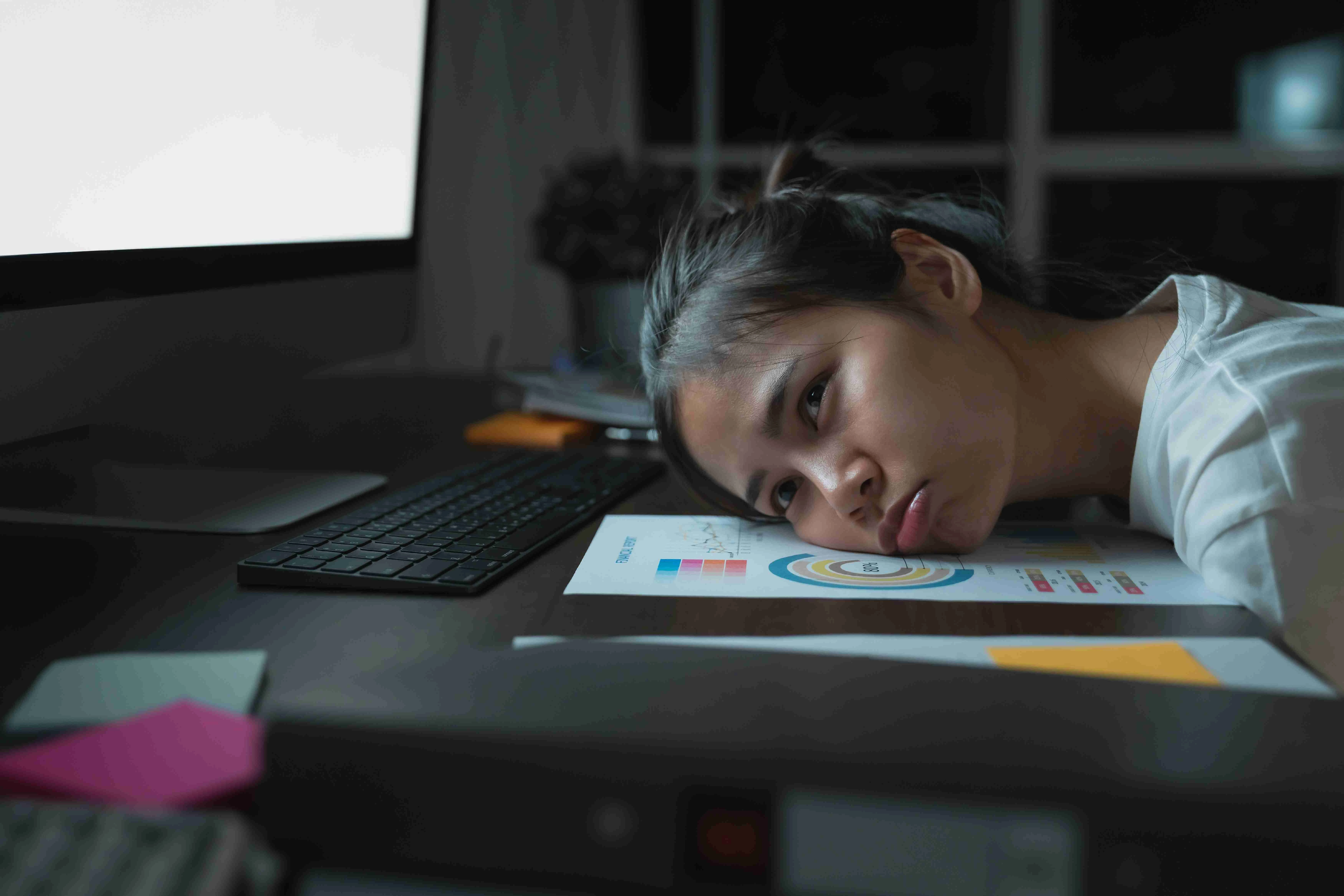 Stressful Asian business woman sitting on the chair and look at the computer screen on office at night.