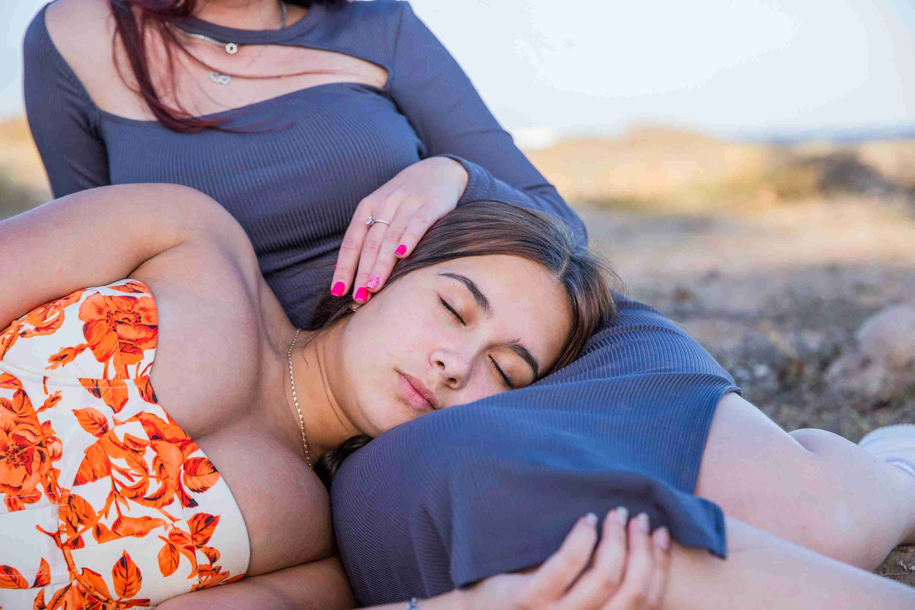 A girl has her head resting on her sister's legs, sisterly love.