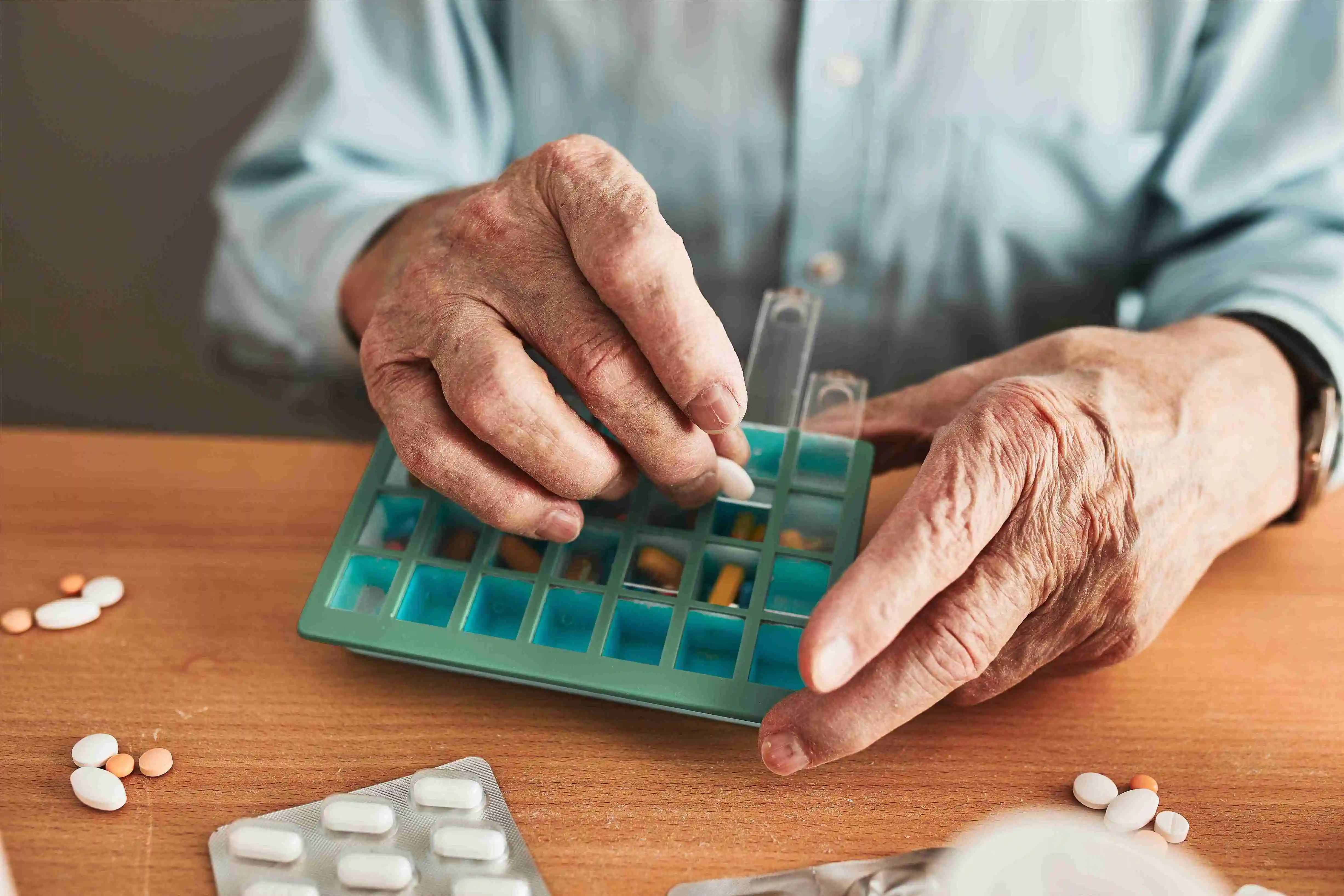 Senior man organizing his medication into pill dispenser. Senior man taking pills from box