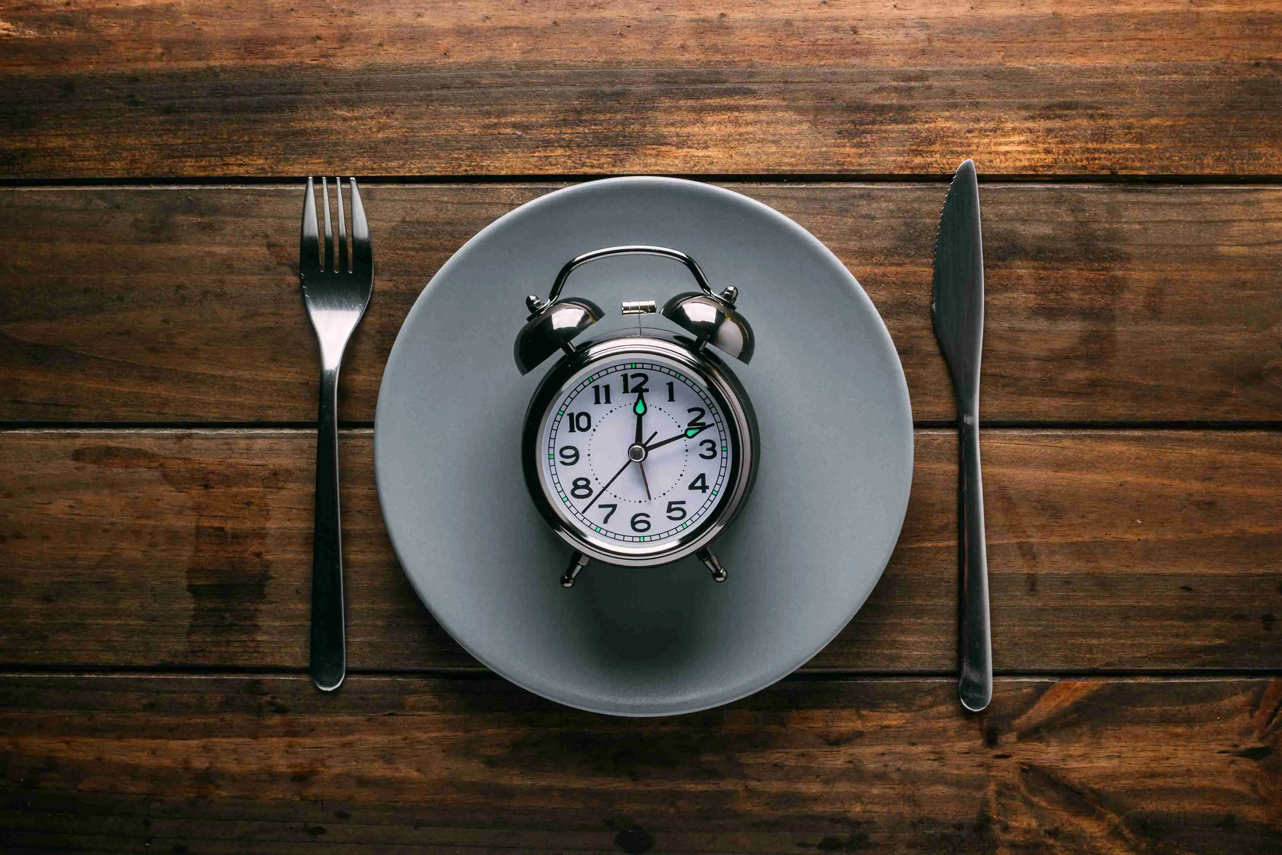 Cutlery near plate with alarm clock