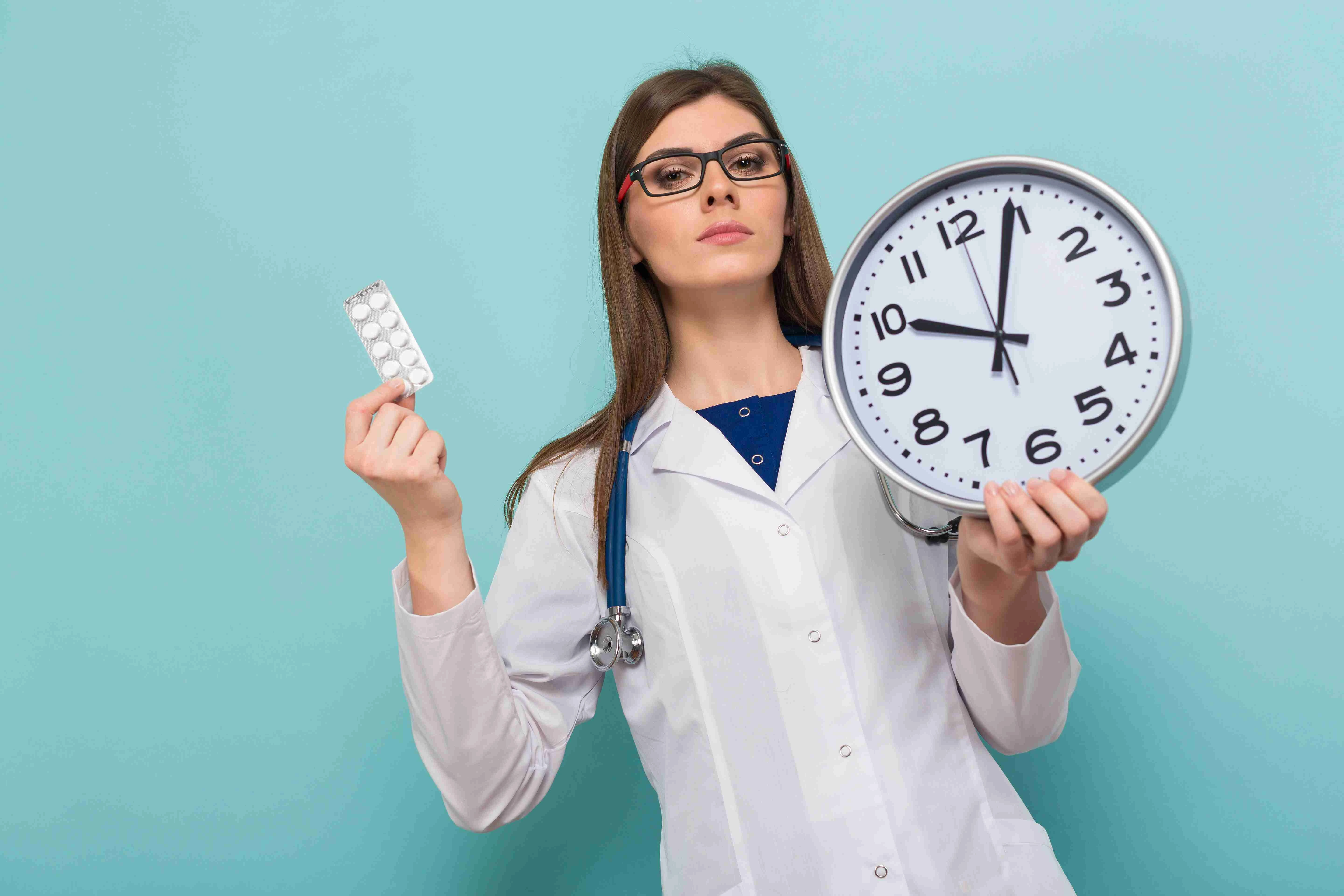 Female brunette doctor in glasses with clock