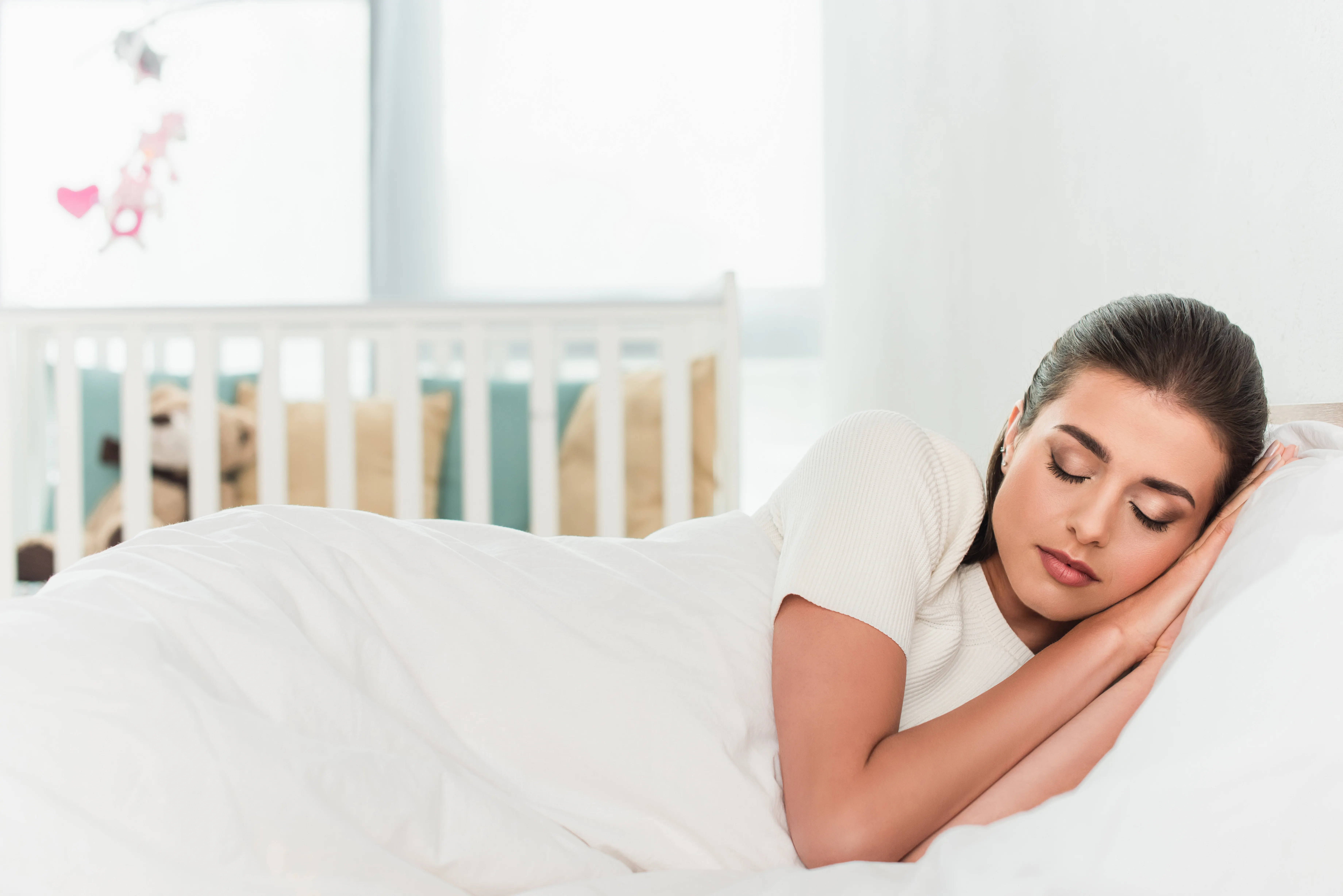 Brunette woman sleeping on white bedding