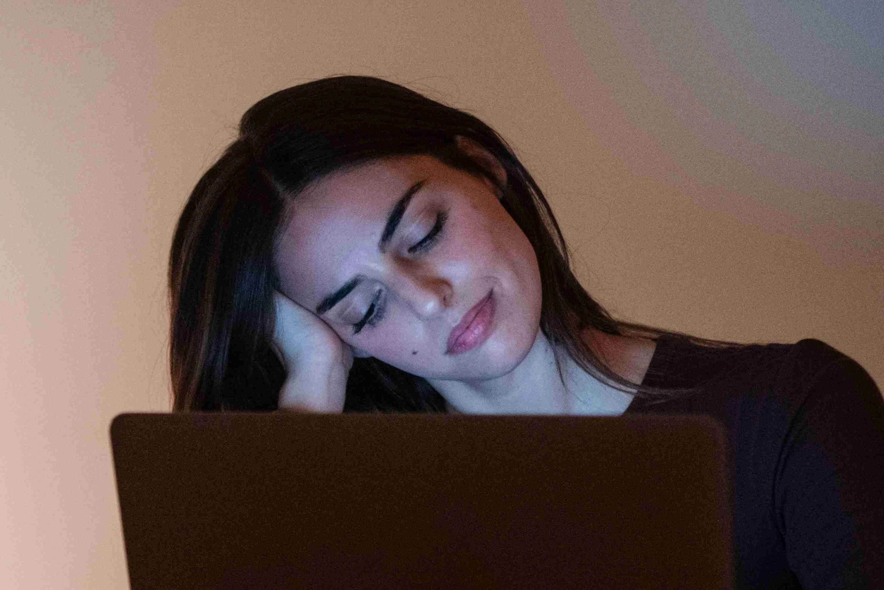 Young pretty smiling woman using laptop in home at night.