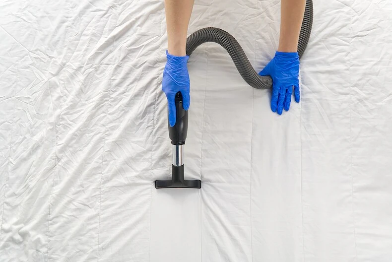 a man cleaning a mattress with a vacuum
