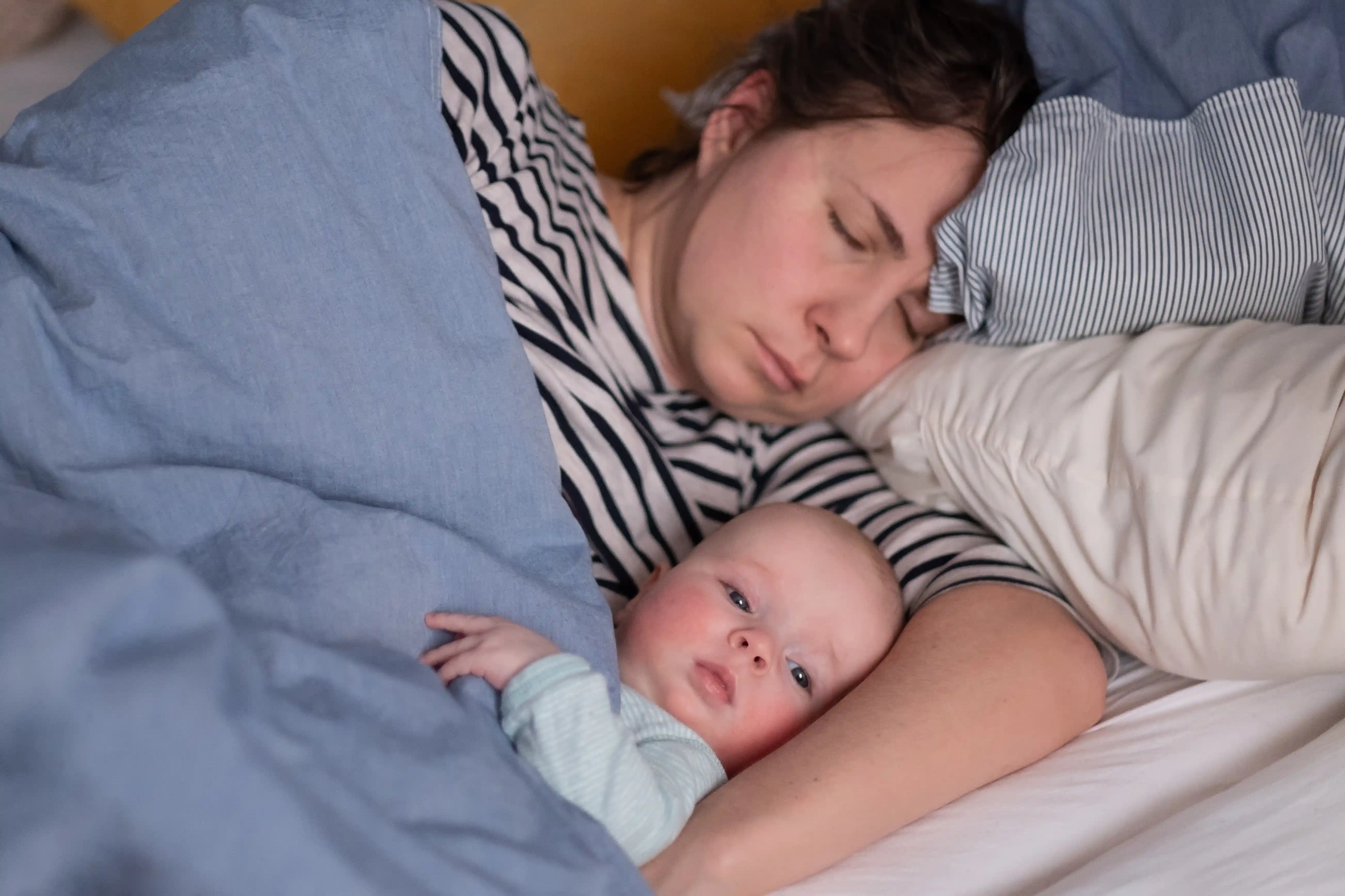 Caucasian young mom and her cute little baby sleeping in bed