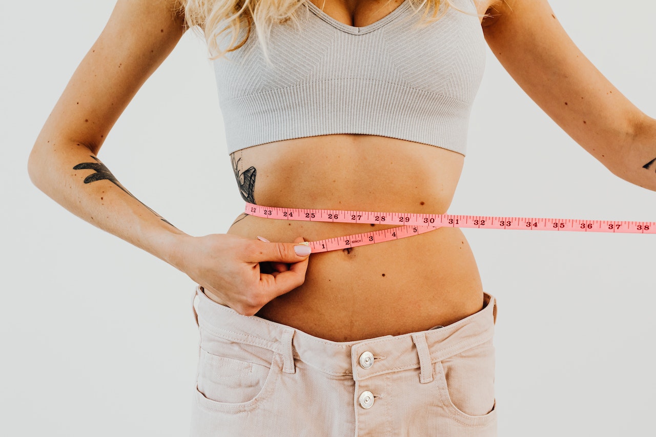 woman measuring waist size with tape