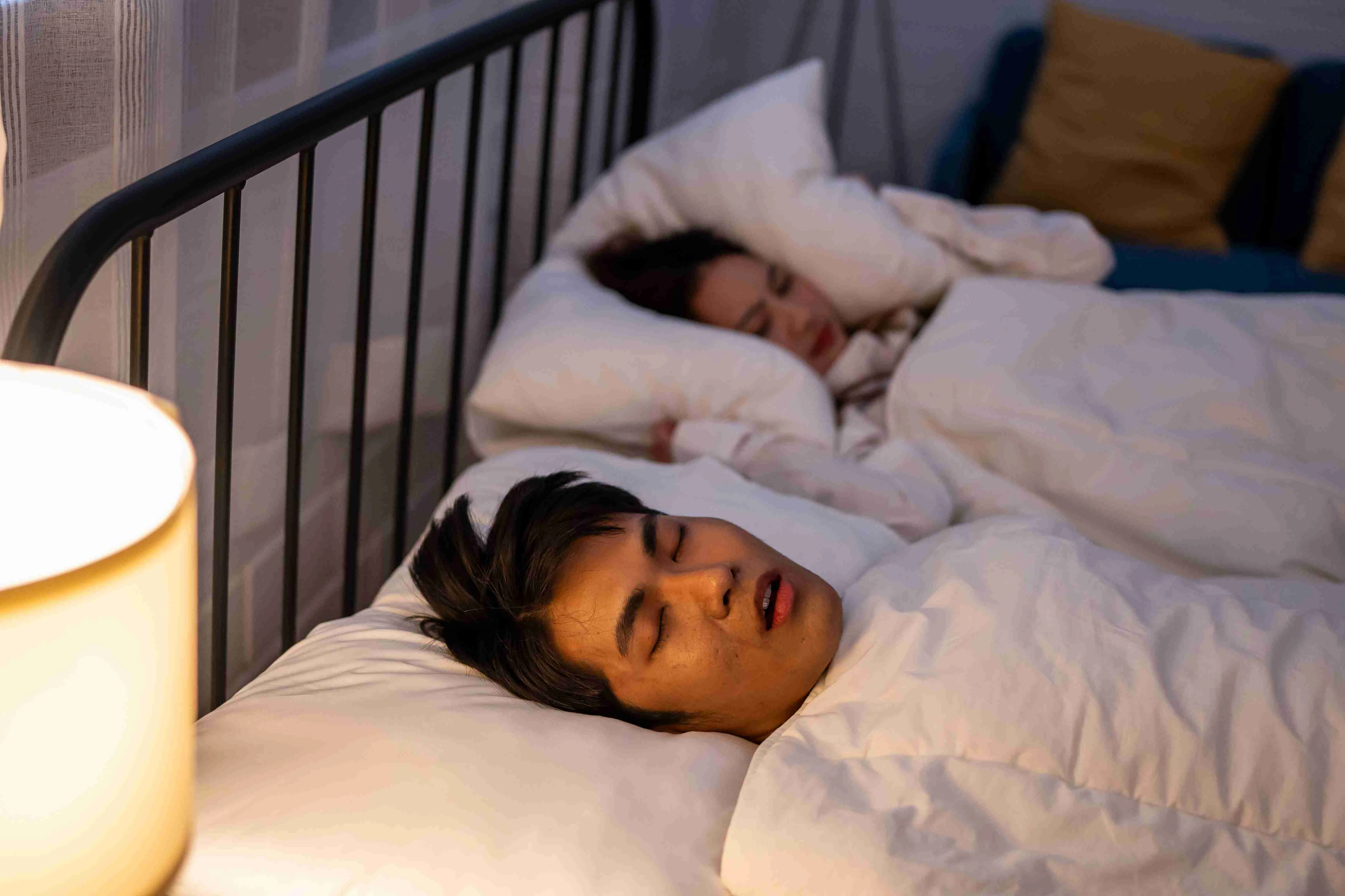 Asian woman feel frustrated from husband snoring while sleep at night.