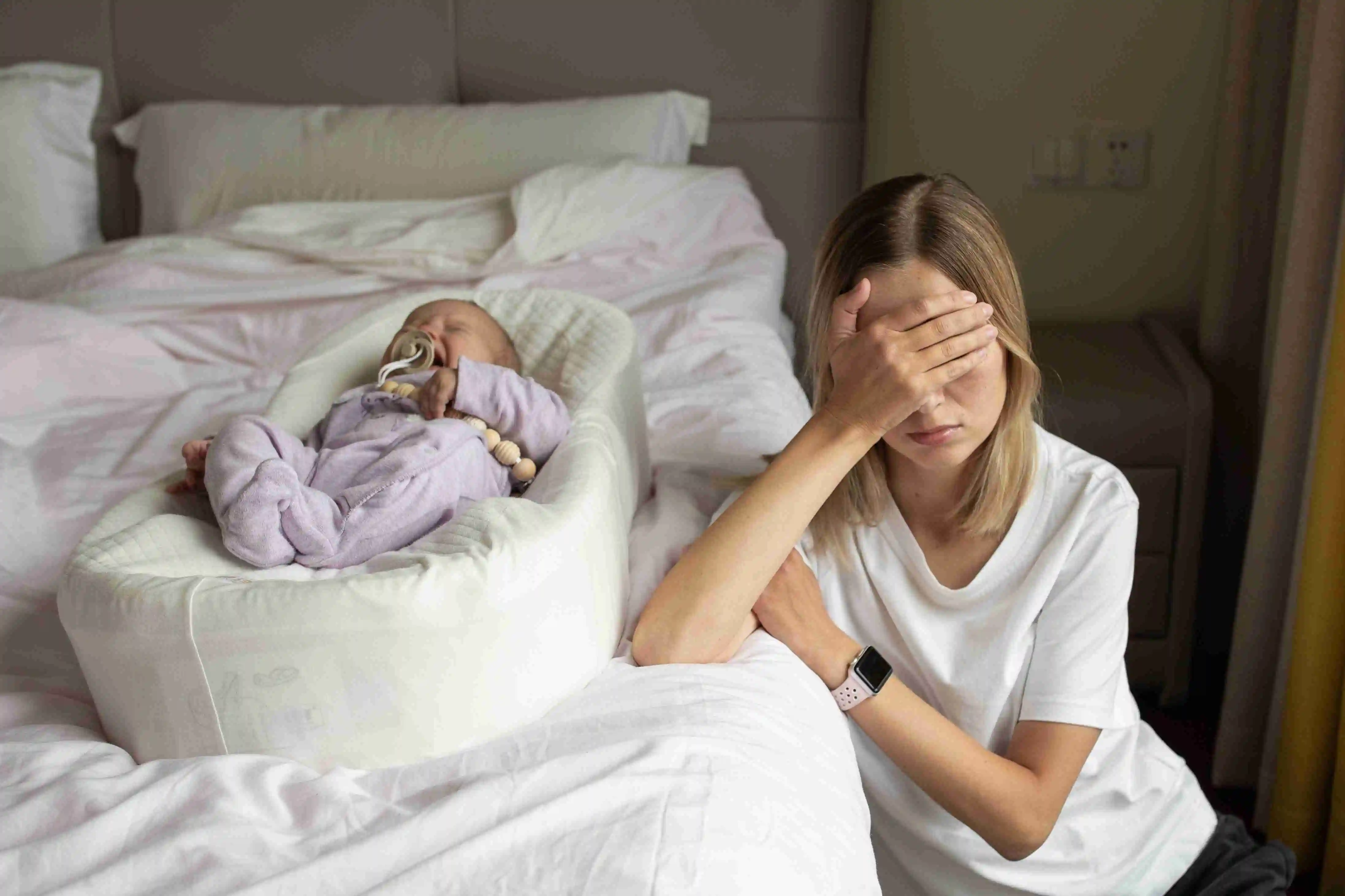 Young Caucasian Mother and baby sitting in bedroom