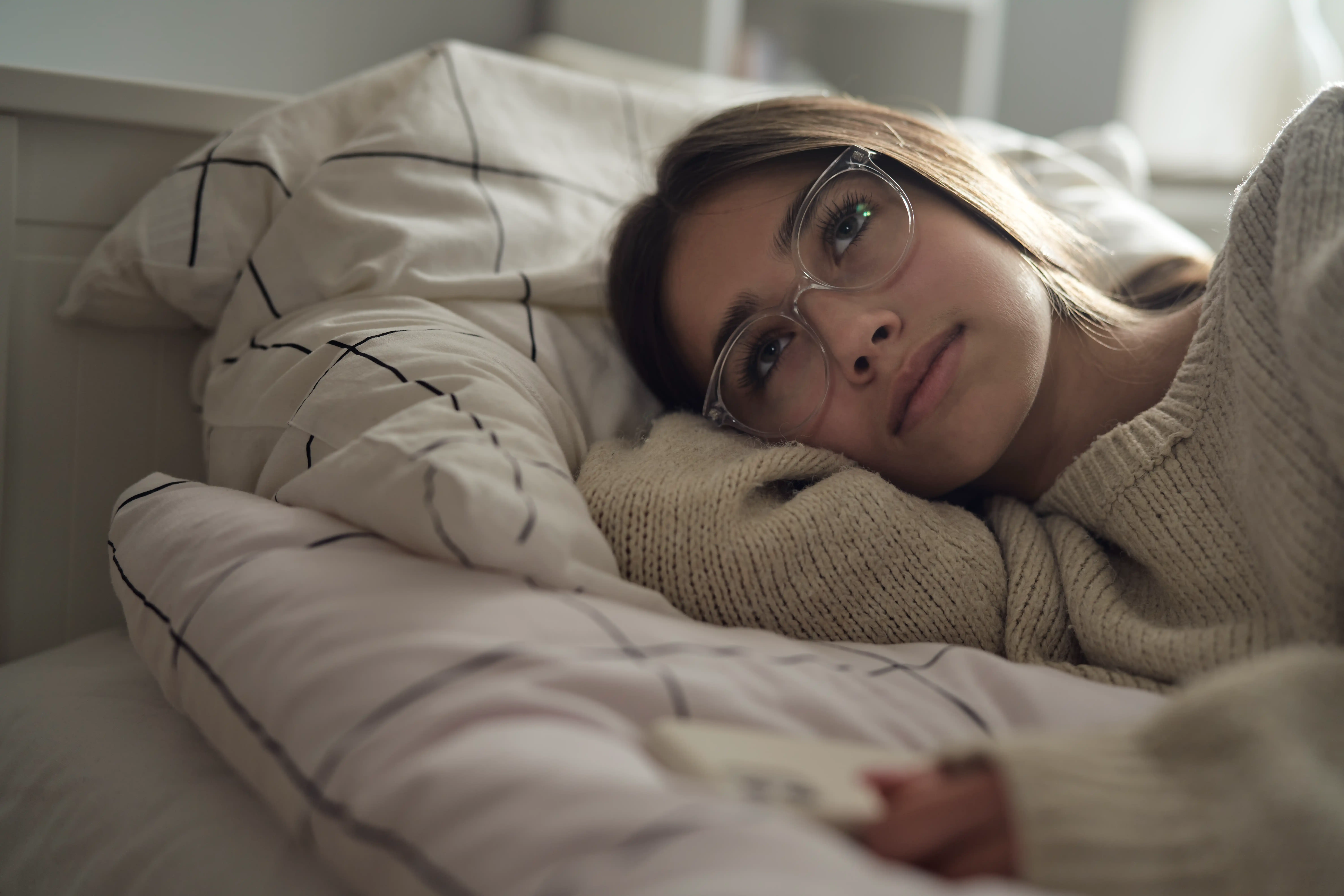 Pensive caucasian teenage girl lying on bed and looking away