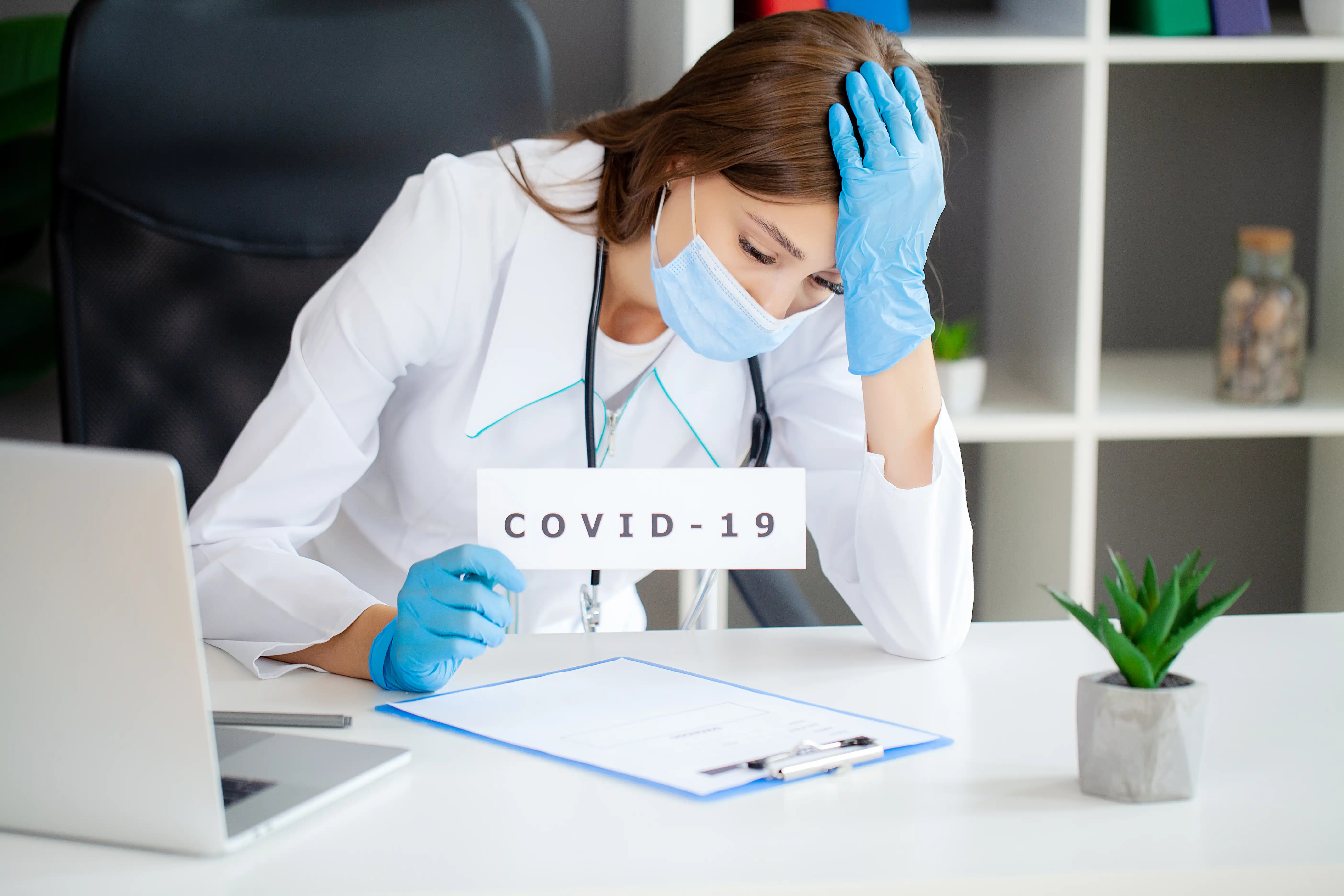 Female doctor in uniform holding a paper signboard lettering covid-19