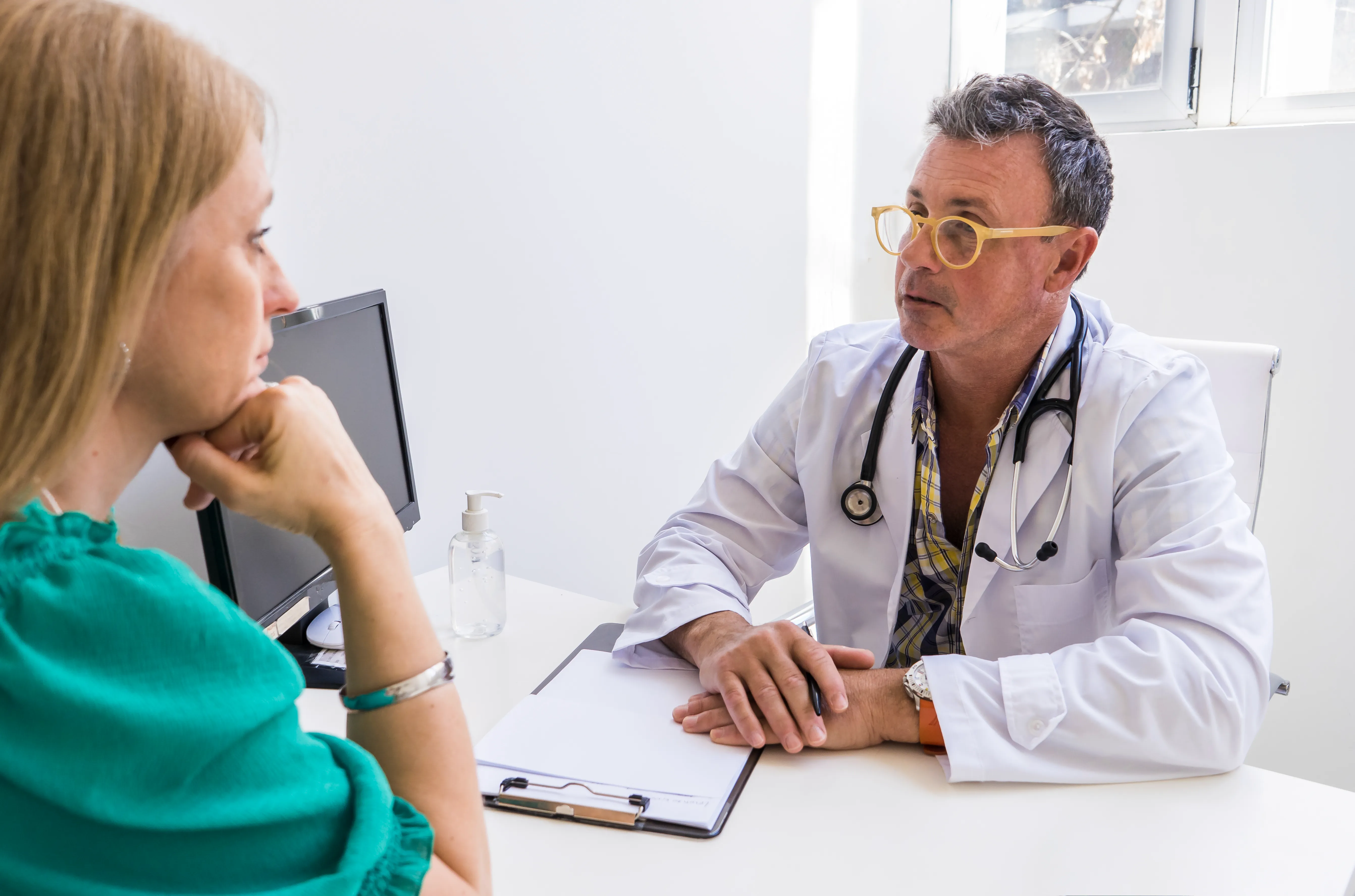 Male doctor telling his patient her diagnostic in his medical office