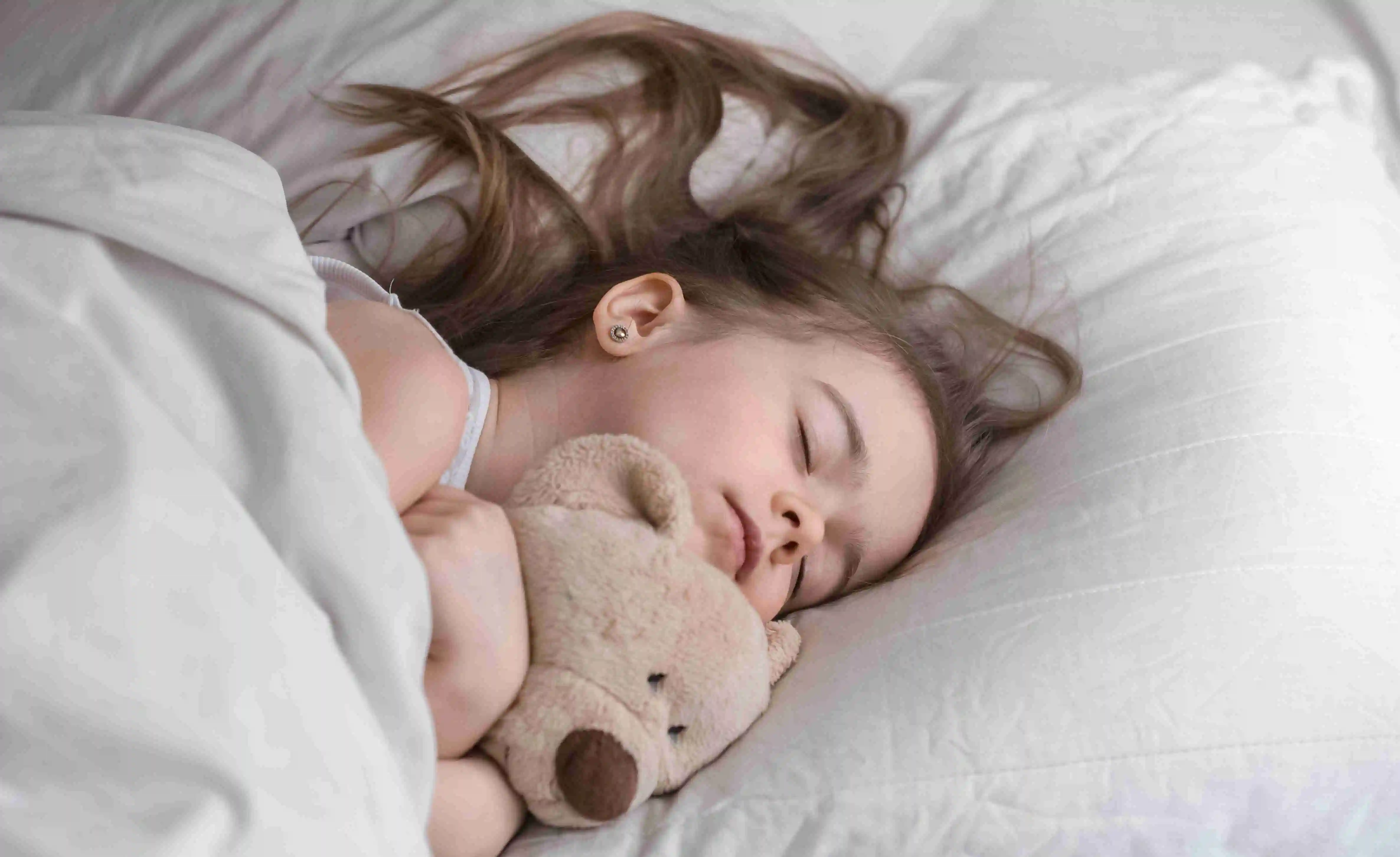 Little cute girl in bed with toy