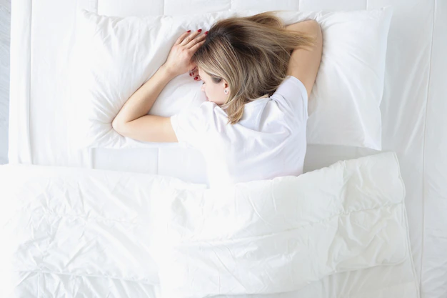 a reviewer sleeping on her stomach on a puffy cloud mattress